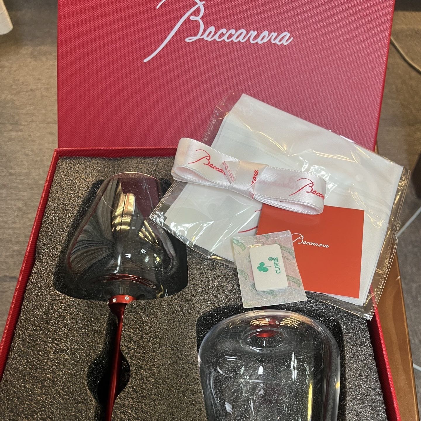 Baccarat crystal glassware gift set features a pair of elegant red-stemmed glasses nestled